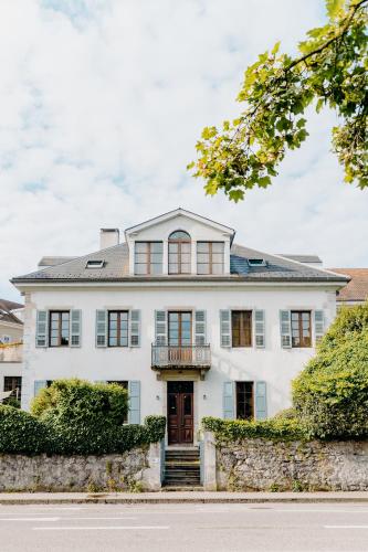 a large white house with a porch at Le Boutik Hotel in Annecy