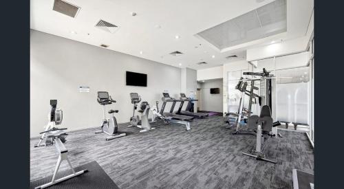 a gym with several tread machines in a room at Rooftop Apartment - Heated Pool & Beach access in Marcoola