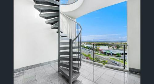 a spiral staircase in a building with a view of a city at Rooftop Apartment - Heated Pool & Beach access in Marcoola
