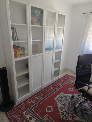 a room with a white book shelf and a chair at Refúgio do Tejo in Tramagal