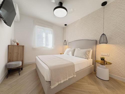 a bedroom with a white bed and a television at Golf y Playa in Roquetas de Mar