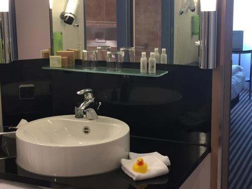 a bathroom with a sink and a mirror at Mövenpick Hotel München-Airport in Hallbergmoos