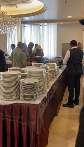 a group of people standing around a table with plates on it at فندق بارك رويال in Al Masfalah