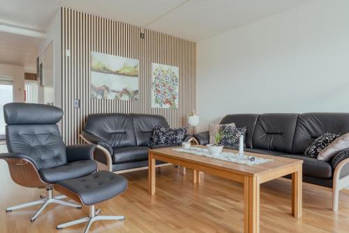 a living room with a couch and a table and chairs at 2 BR Ocean and City View Apartment in Tórshavn