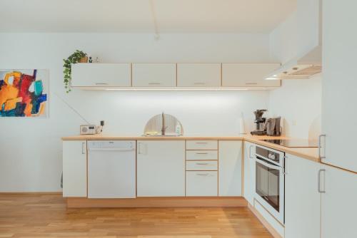 a kitchen with white cabinets and white appliances at 2 BR Ocean and City View Apartment in Tórshavn