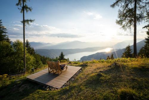 a person sitting on a bench on a wooden boardwalk at Alpenhof M&E in Bad Kleinkirchheim