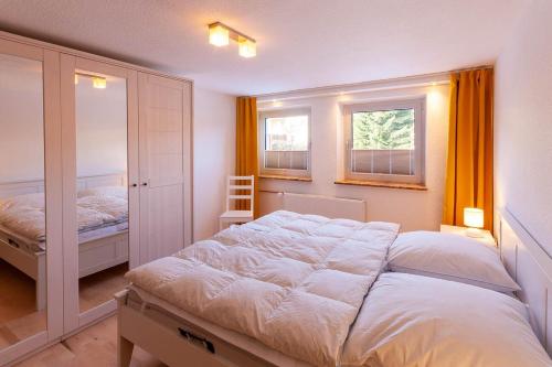 a bedroom with a large white bed and two windows at Ferienhaus Holzwurm in Braunlage