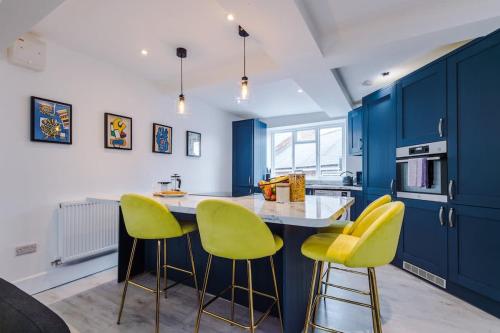a kitchen with blue cabinets and yellow bar stools at The Art House Ruthin - 3-Bed 3-Ensuite in Ruthin