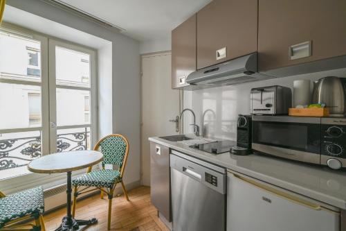 - une cuisine avec une table, des chaises et un comptoir dans l'établissement French typical apartment (opéra 5D), à Paris
