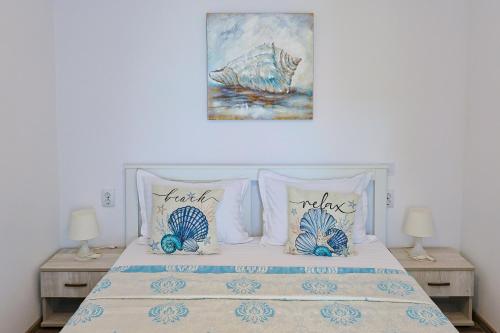 a bedroom with a bed with pillows and a painting at Casa EMMA in Jurilovca