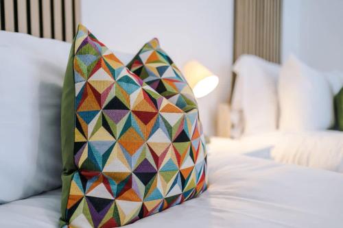 a colorful pillow sitting on top of a bed at The Art House Ruthin - 3-Bed 3-Ensuite in Ruthin