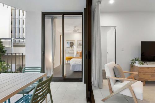 a living room with a table and chairs and a bedroom at The Cosmopolitan Suite in Maroochydore