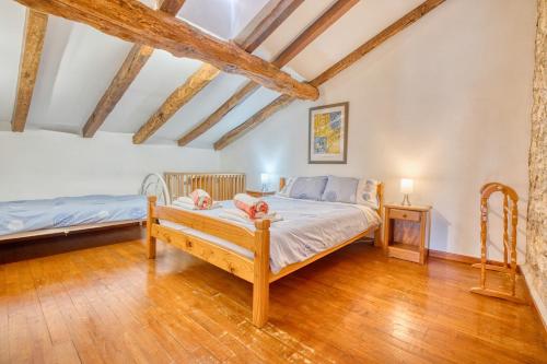 Un dormitorio con una cama y suelo de madera. en La Ferme, en Razac-dʼEymet
