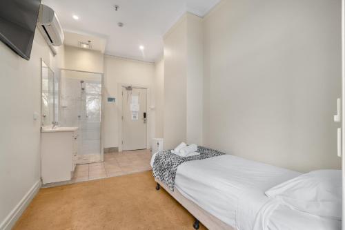 a bedroom with a bed and a bathroom with a shower at Royal Hotel Orange in Orange