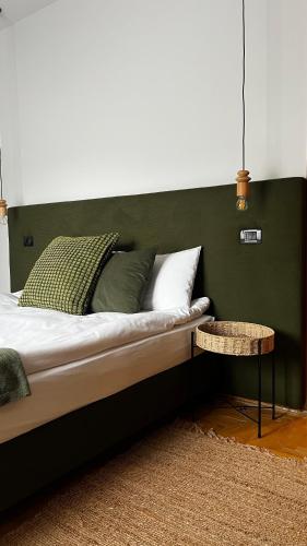 a bed with a green headboard and a table at Pensiunea Alpin Predeal in Predeal