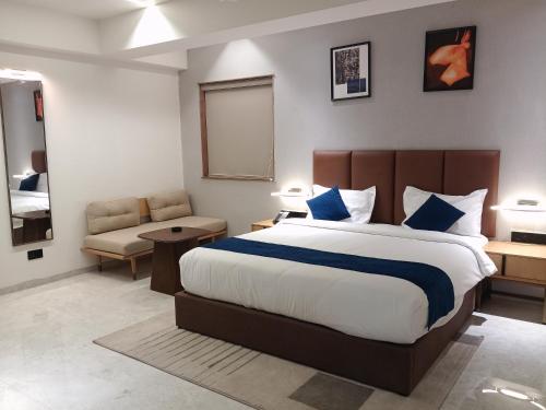 a bedroom with a large bed and a chair at Lords Eco Inn Jamnagar - Maheshwari Nagar in Jamnagar
