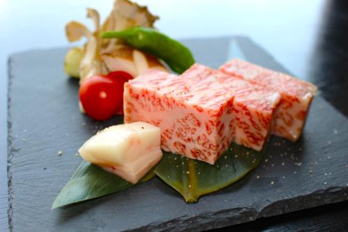 a black plate with different types of food on it at 坂本屋旅館 in Kyotango