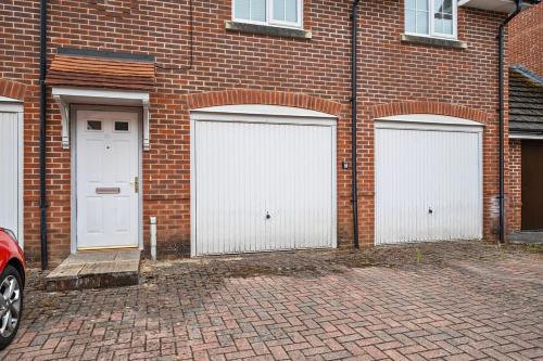 three white garage doors on the side of a brick building at MODERN 2 BED APARTMENT LOCATED CHINEHAM BUSINESS PARK with FREE PARKING, WIFI, NETFLIX BY AI ESTATE GROUP in Basingstoke