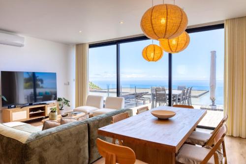 ein Wohnzimmer mit einer Couch und einem Tisch und Stühlen in der Unterkunft Villa Arco-Iris, a Home in Madeira in Arco da Calheta