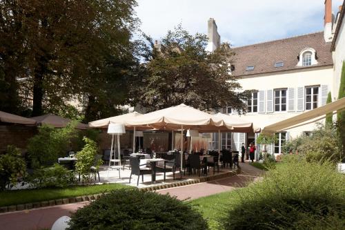 a patio with tables and umbrellas in front of a building at Maison Philippe Le Bon in Dijon
