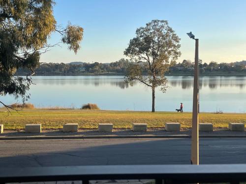 a person walking on a sidewalk near a lake at Luxury Lake Front Living in Lake Albert