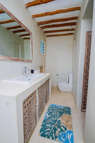 a bathroom with a sink and a mirror and a toilet at Luxus Ahadi-Beachfront-Villa mit Pool & Strandzugang bei Mtwapa Mombasa in Mombasa
