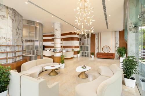 a lobby with white chairs and tables and a chandelier at Nexstay De' Malabaricus in Kozhikode