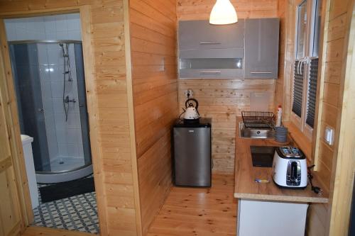 a small kitchen with a sink and a shower at Domki u Ani Rusinowo in Rusinowo