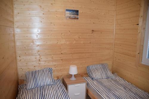 two beds in a room with wooden walls at Domki u Ani Rusinowo in Rusinowo