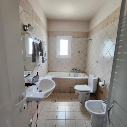 a bathroom with two sinks and a tub and a toilet at Potamos Townhouse & Shared Garden in Potamós