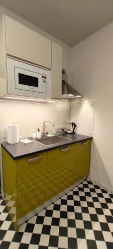 a kitchen with a sink and a microwave at Chessboard apartment in old town Riga, Coffee included in Rīga