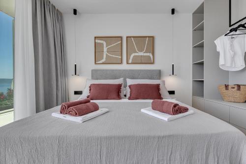a white bedroom with a large bed with red pillows at Villa Fragment with private Jacuzzi - Makarska Exklusiv in Brela