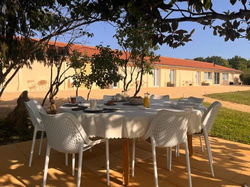 Una mesa con sillas blancas y un mantel blanco. en lelotusnoir-Périgord, en Mazeyrolles