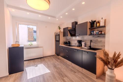 a large kitchen with black cabinets and a window at Rhein-Lodge in Urbar-Mayen-Koblenz