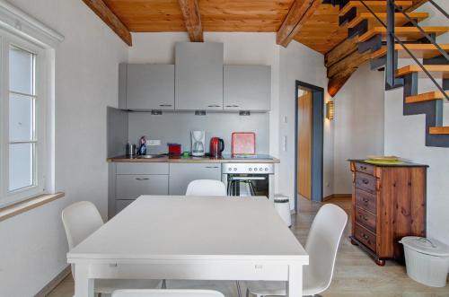 a kitchen with a white table and white chairs at Escasa Ferienwohnungen in Heiligenberg