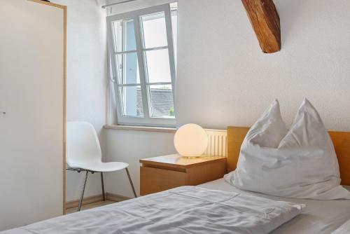 a bedroom with a bed with white pillows and a window at Escasa Ferienwohnungen in Heiligenberg