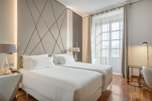 a bedroom with a large white bed and a window at NH Collection Salamanca Palacio de Castellanos in Salamanca