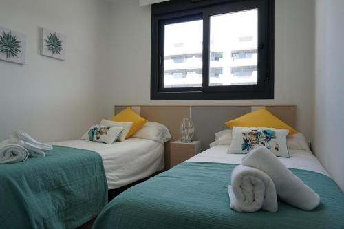 a room with two beds with towels on them at Lovely modern two bedroom apartment in Arenales del Sol