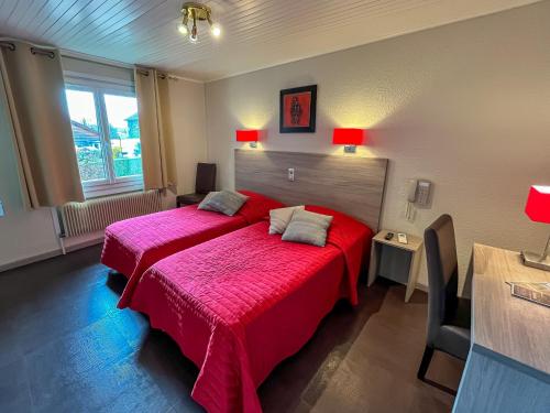 a bedroom with a red bed with a red blanket at La Bonne Auberge in Ségny