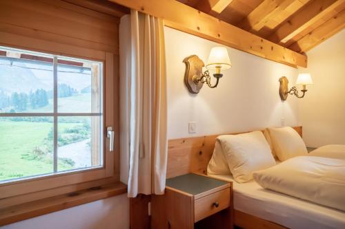 a bedroom with a bed and a window at Hotel Chesa Pool in Sils Maria