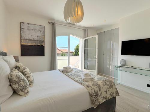 une chambre avec un grand lit avec une grande fenêtre dans l'établissement Villa Tassinia, à Cannes