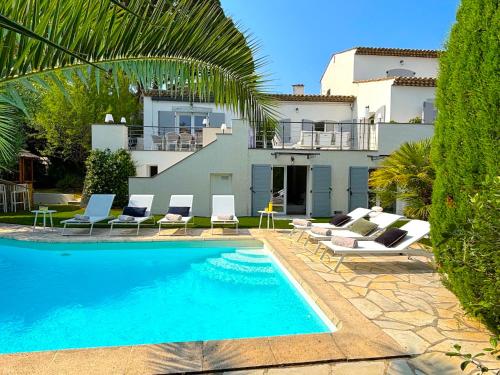 une piscine avec des chaises longues et une maison dans l'établissement Villa Tassinia, à Cannes