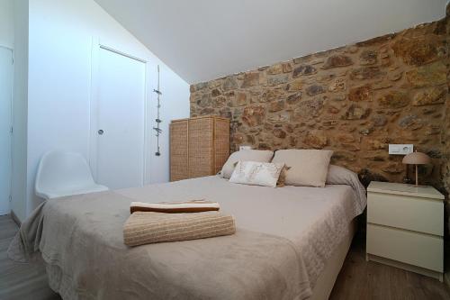 a bedroom with a large bed with a stone wall at Preciosa casa en Playa de Razo in Carballo