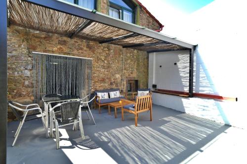 a patio with chairs and a table and a building at Preciosa casa en Playa de Razo in Carballo