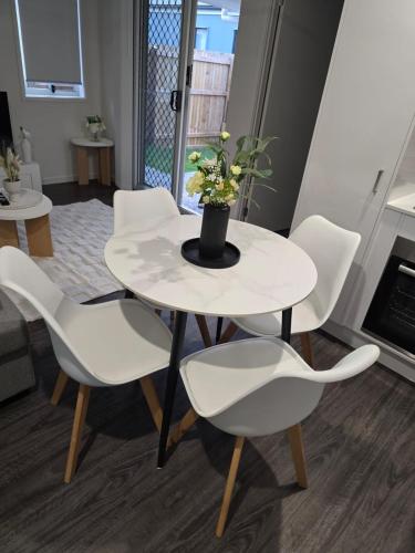 a white table with white chairs and a vase with flowers at The Gateway to Sunshine State in Loganlea