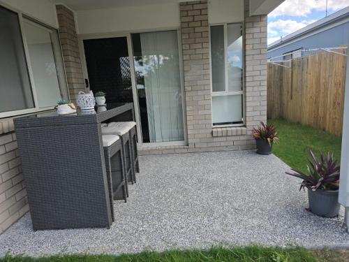 a patio with a table and chairs in front of a house at The Gateway to Sunshine State in Loganlea