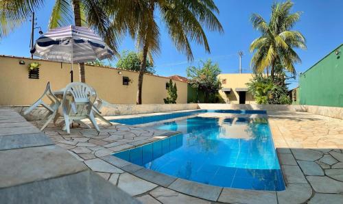 einen Pool mit einem Stuhl und einem Sonnenschirm in der Unterkunft Área de Lazer Sertãozinho in Sertãozinho