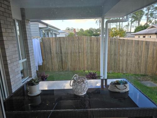 a patio with a glass table and a fence at The Gateway to Sunshine State in Loganlea