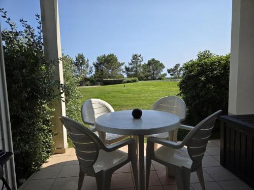 a table and chairs on a patio with a view of a field at Appartement terrasse, piscines, wi-fi, résidence face mer in Les Sables-dʼOlonne