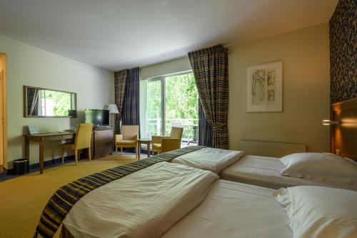 a large bed in a hotel room with a desk at Hotel Watermolen Le Mirage in Kasterlee